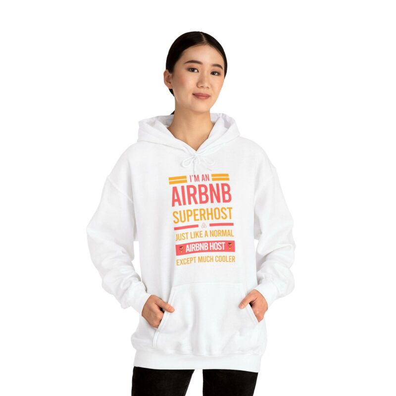 A person wearing the 'I'm an Airbnb Superhost Unisex Heavy Blend Hooded Sweatshirt,' which features the phrase "I'M AN AIRBNB SUPERHOST, just like a normal Airbnb host except much cooler.