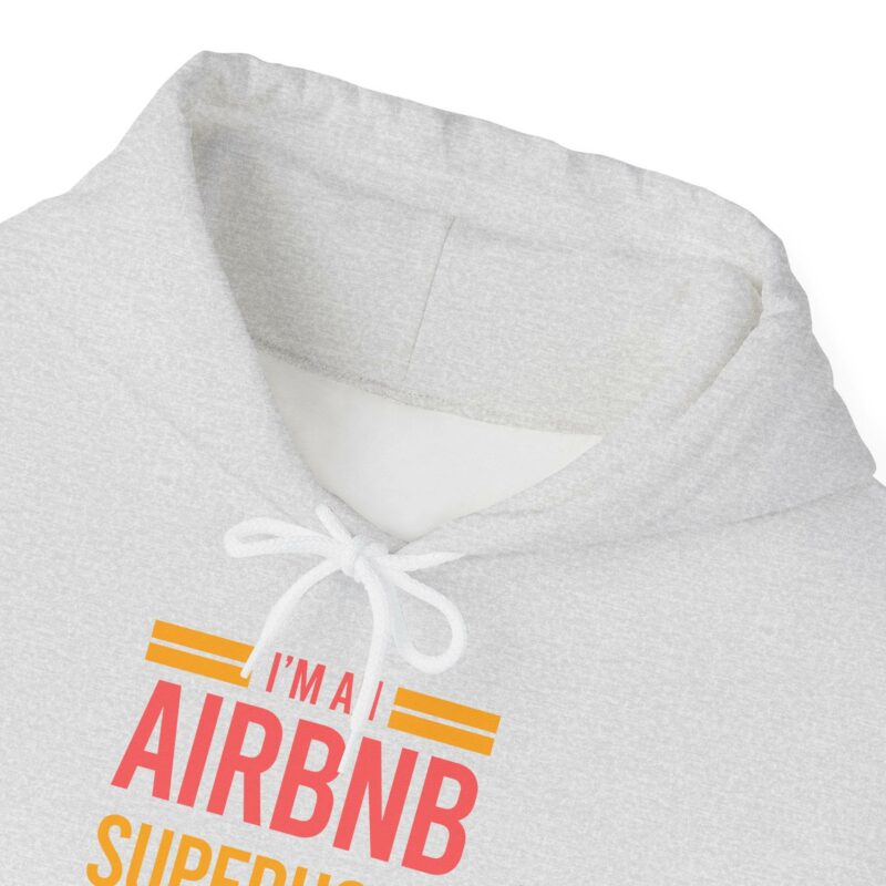 A unisex heavy blend hooded sweatshirt in gray, complete with white drawstrings and the bold text "I'm an Airbnb Superhost" in vibrant orange and pink letters.