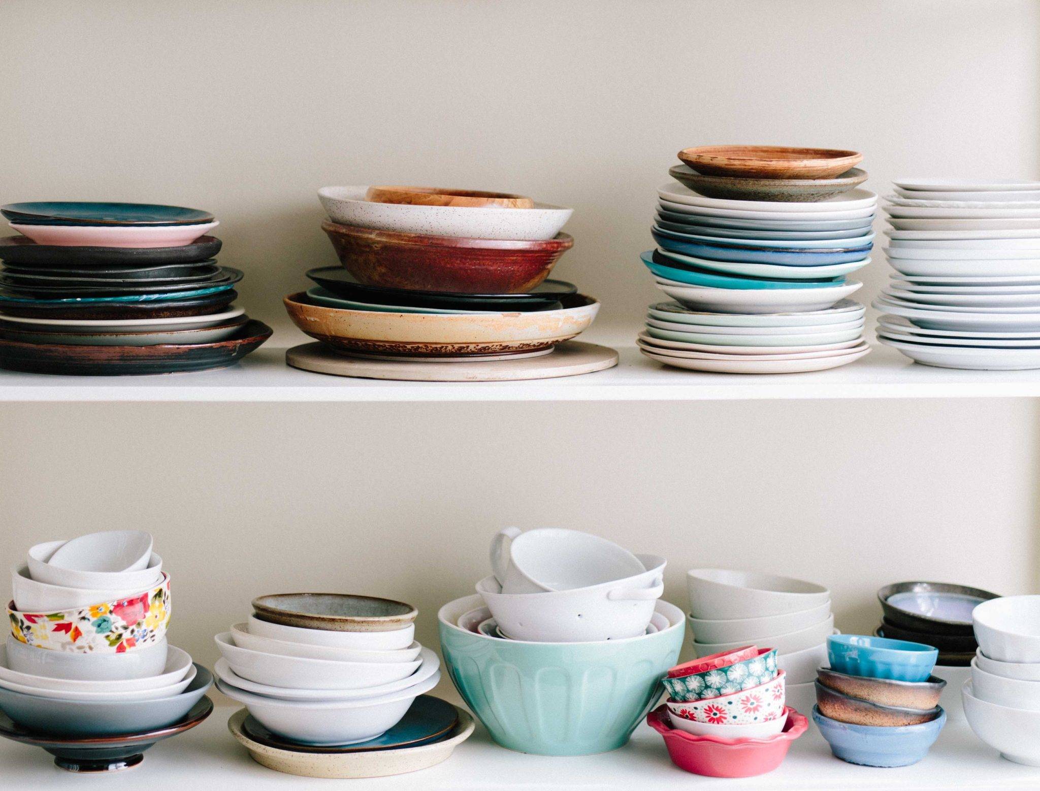 Airbnb Hosting An Airbnb hosting setup showcasing a collection of plates and bowls on a white shelf.