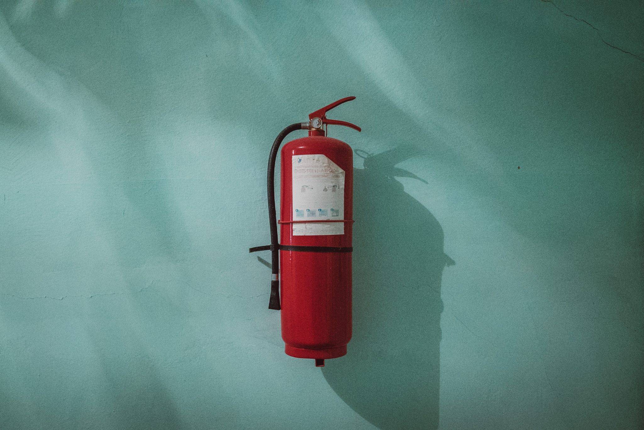 Airbnb Hosting A fire extinguisher in an Airbnb hosting space with a distinct red color, contrasting against the blue wall.