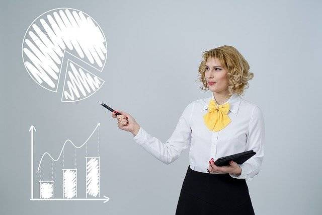 Airbnb Hosting A businesswoman illustrating a pie chart on a grey background to improve Airbnb business strategies.