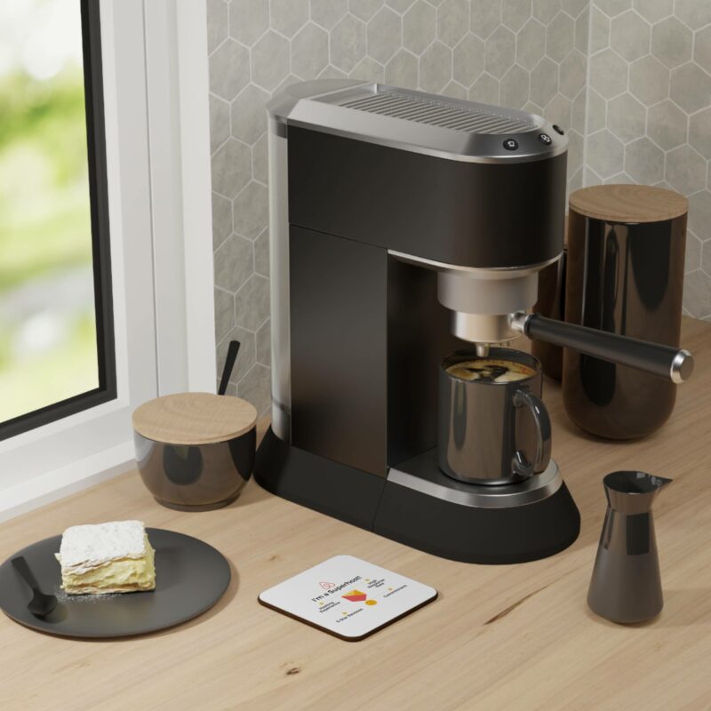 A modern espresso machine on a kitchen counter next to a slice of cake, an "I'm an Airbnb Superhost" hardboard back coaster, a small jug, and two storage containers with wooden lids.