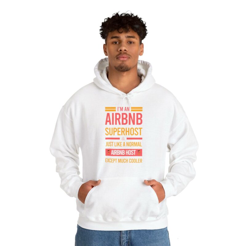 Person wearing an "I'm an Airbnb Superhost Unisex Heavy Blend Hooded Sweatshirt" with the text "I'm an Airbnb Superhost - Just Like a Normal Airbnb Host Except Much Cooler," standing with hands in the front pocket of the hoodie.