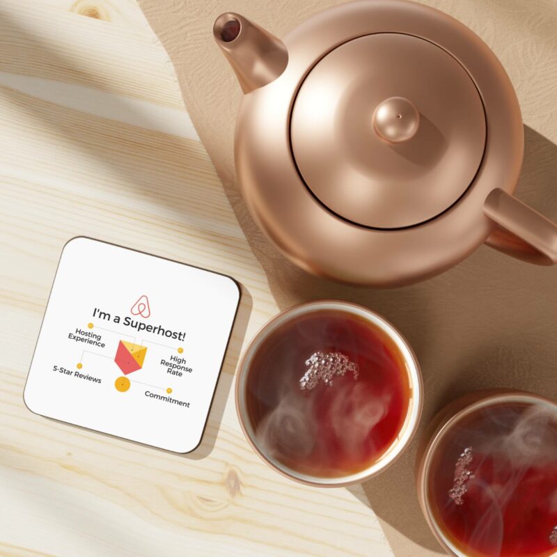 A copper teapot and two cups of tea on a wooden table next to an "I'm an Airbnb Superhost" hardboard back coaster highlighting hosting experience, high rating, 5-star reviews, and commitment.