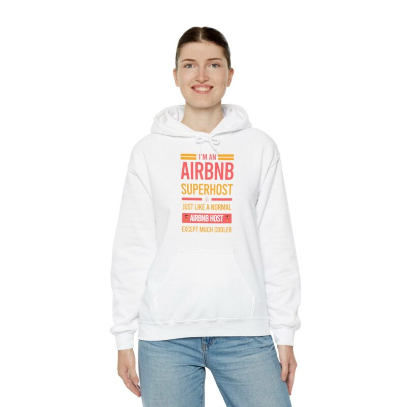 A person stands against a white background wearing the "I'm an Airbnb Superhost Unisex Heavy Blend Hooded Sweatshirt," which features the text, "I'm an Airbnb Superhost. Just like a normal Airbnb host except much cooler.