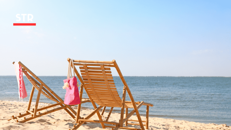 Airbnb Hosting Two cozy wooden chairs on the beach.