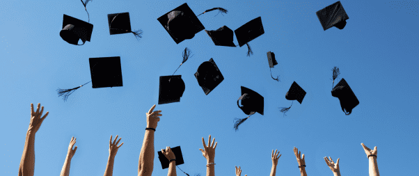 Airbnb Hosting A group of people tossing graduation hats into the air while capturing the joyful moment with their Airbnb guests.