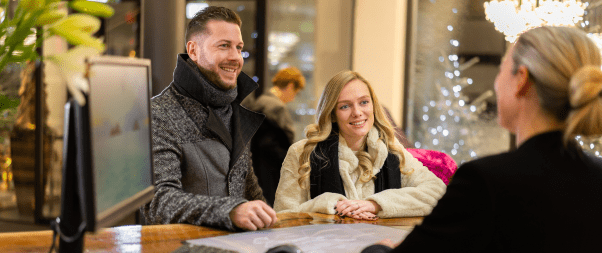 Airbnb Hosting A man and a woman smiling at a desk in an Airbnb hotel.