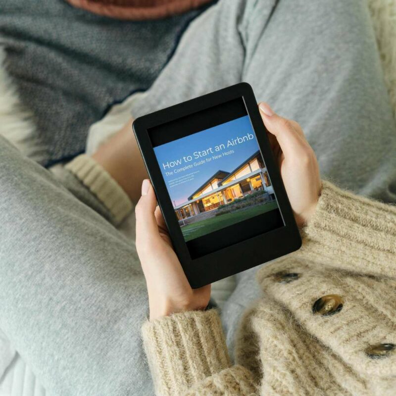 Airbnb Hosting A woman holding a tablet featuring "How to Start an Airbnb, The Complete Guide for New Hosts" templates.