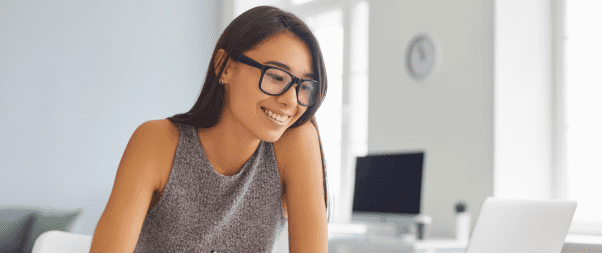 Airbnb Hosting A woman wearing glasses is sitting at a desk with a laptop, learning how to put her Airbnb on autopilot.