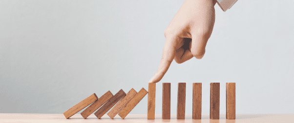 Airbnb Hosting A woman's hand is pointing at a wooden dominoes tower while utilizing the NoiseAware and Party Squasher Review, which offer smart solutions for monitoring your Airbnb.